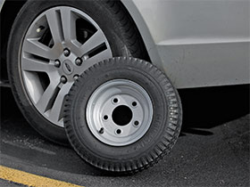 Picture of a Bruno Joey spare tire next to a car
