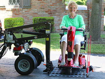 Customer driving mobility device on to Bruno Chariot platform