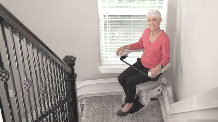 Woman riding a Bruno Elite curved indoor stair lift on a landing