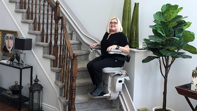 Woman riding upstairs on a Bruno Elite Curved stairlift
