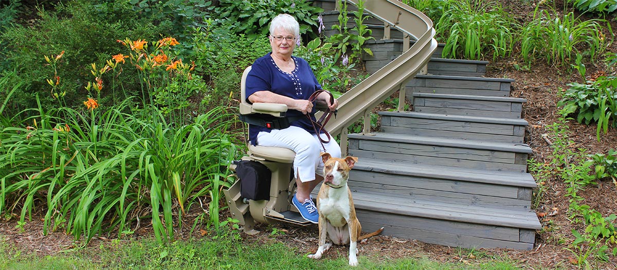 Bruno Elite Outdoor Curved Stairlift on deck steps with woman and dog