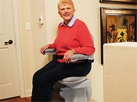 Woman on Elite Curved stairlift at top of the stairs
