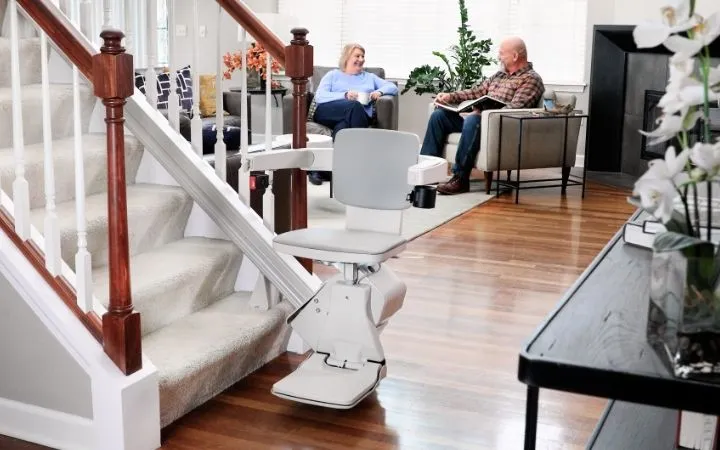 an elderly women riding an elite straight indoor stair lift