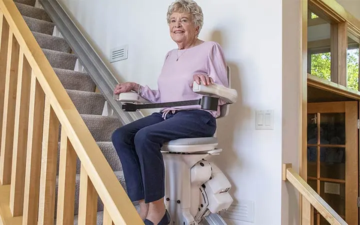 an elderly women riding an elite straight indoor stair lift