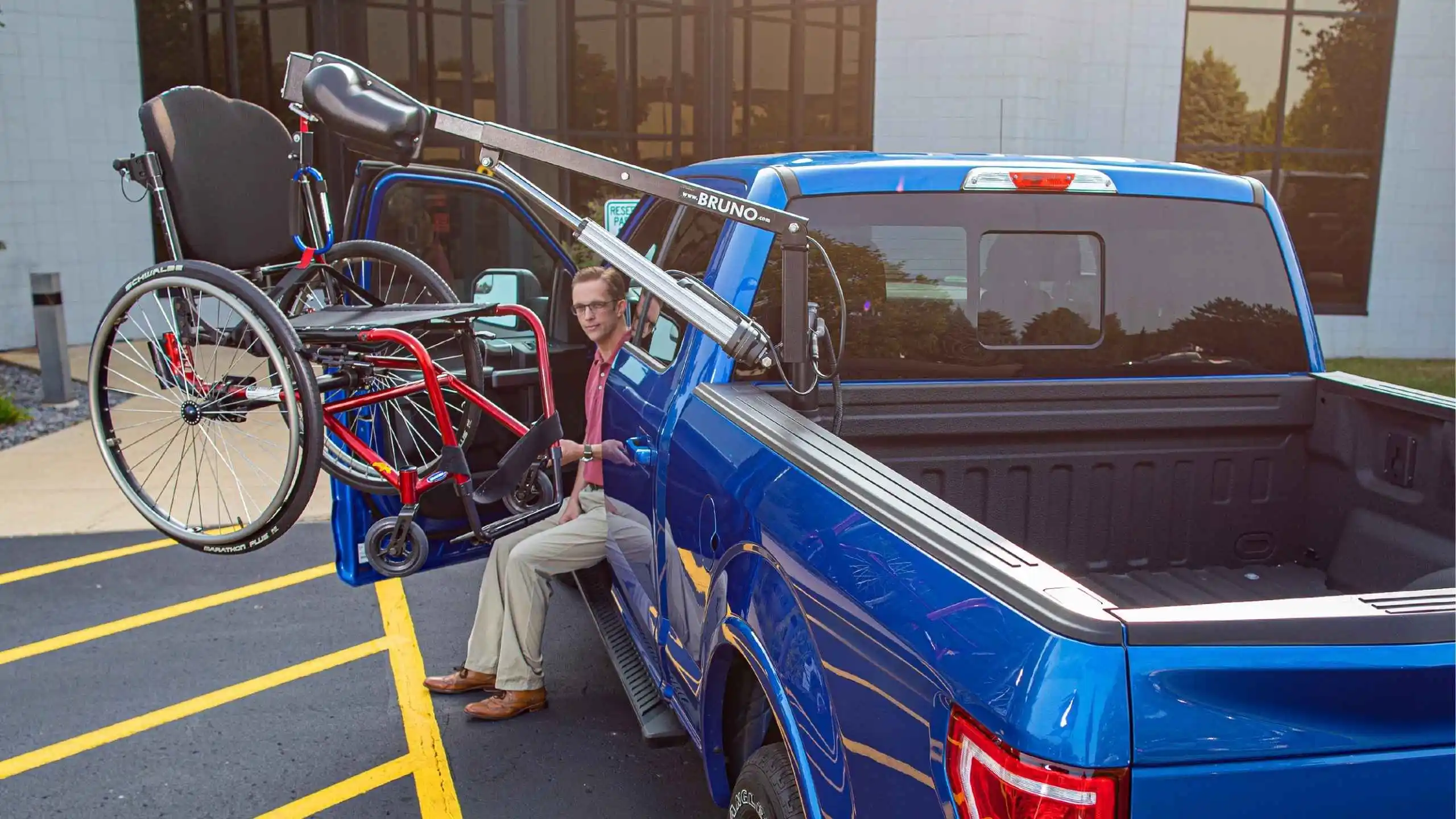 a man sitting in the back of a blue truck with a bicycle and a crane