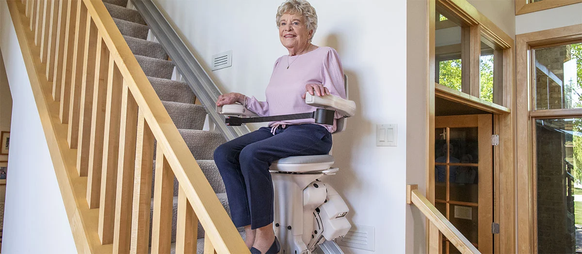 an elderly women riding an elite straight indoor stair lift