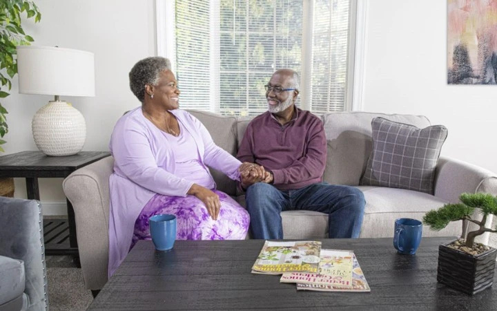 happy couple holding hands while sitting on a couch