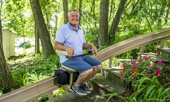 Mann in einem blauen Hemd fährt einen Treppenlift im Freien
