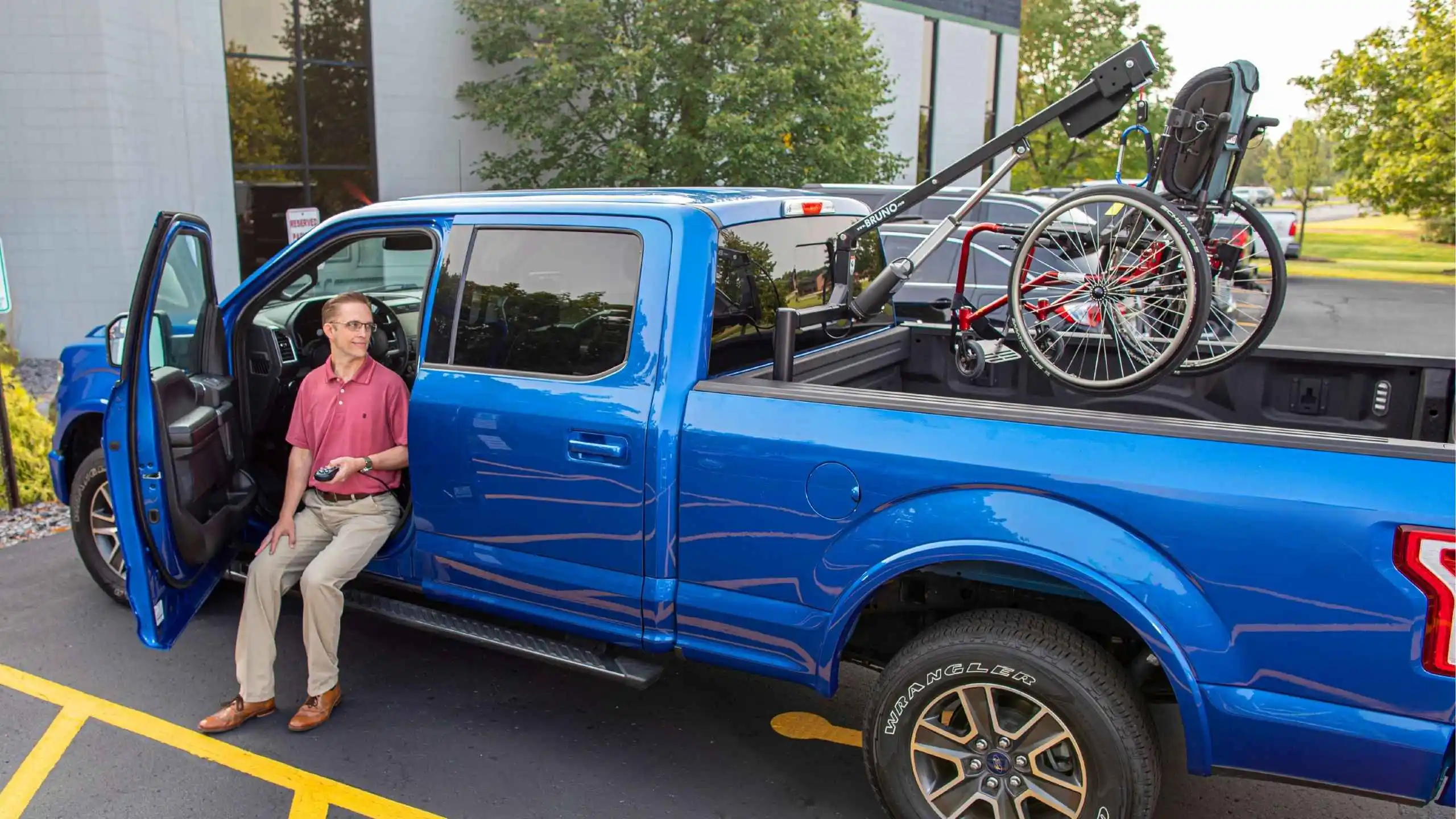 a man sitting on a blue truck with a bicycle on the back