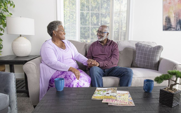 happy couple holding hands while sitting on a couch